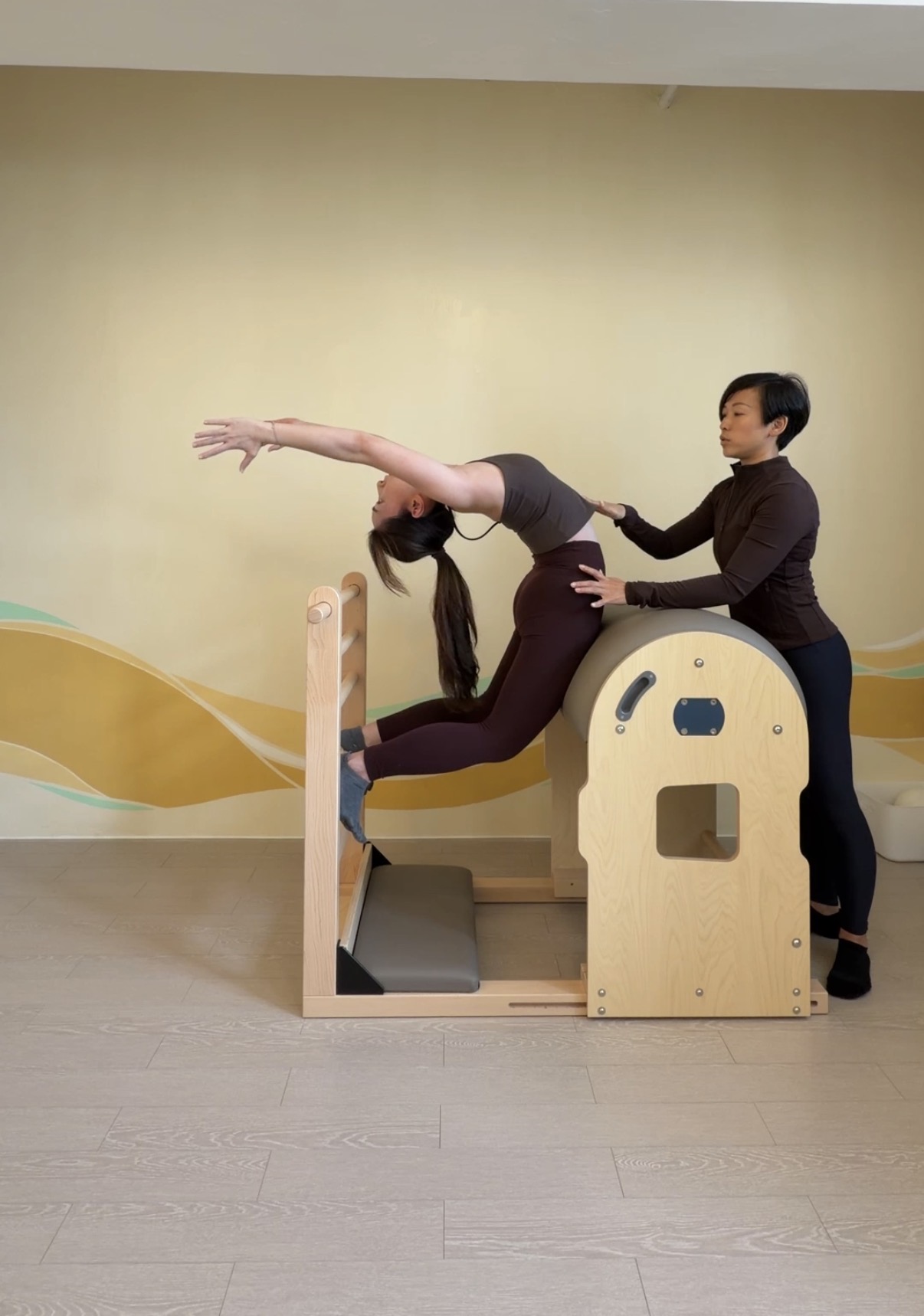 An OMIYOGA teacher guiding a student on Pilates apparatus